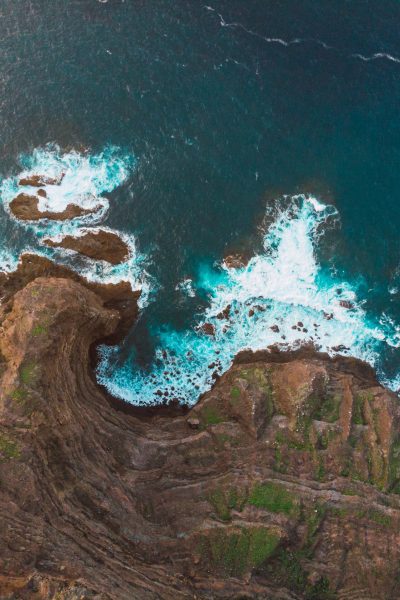 Drone view from above of coastal cliffs with waves of ocean dashing against making white foam, Spain